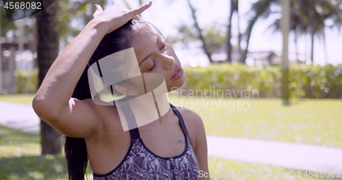 Image of Tired Asian woman rubbing head with closed eyes in park