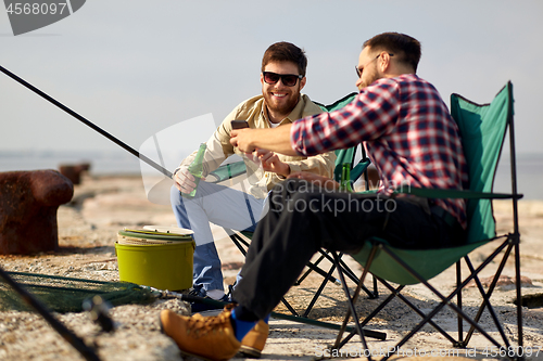 Image of friends with smartphone and beer fishing on pier