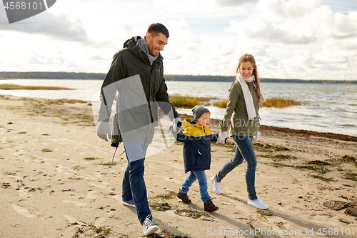 Image of happy family walking along autumn beach