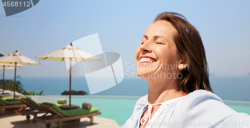 Image of happy woman enjoying sun over infinity edge pool