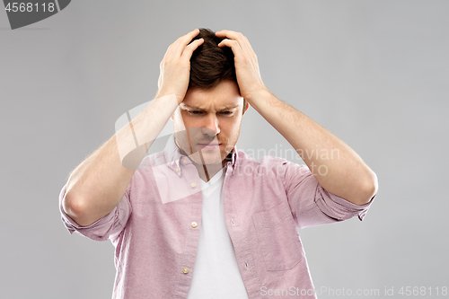 Image of unhappy young man suffering from headache