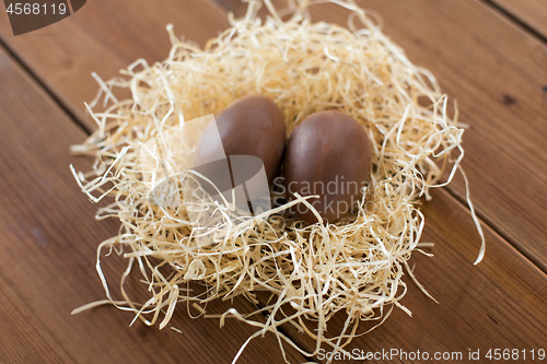 Image of chocolate eggs in straw nest on wooden table