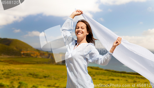 Image of happy woman with shawl waving in wind over big sur