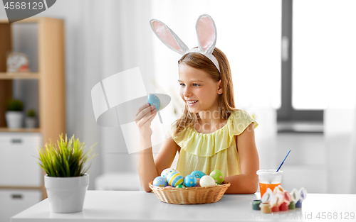 Image of happy girl with colored easter eggs at home