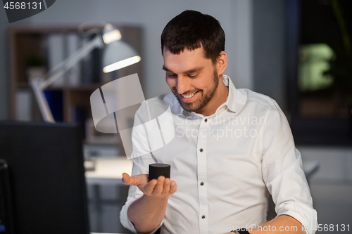 Image of businessman using smart speaker at night office