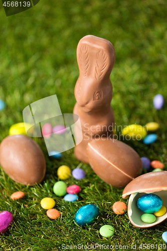 Image of chocolate bunny, eggs and candy drops on grass