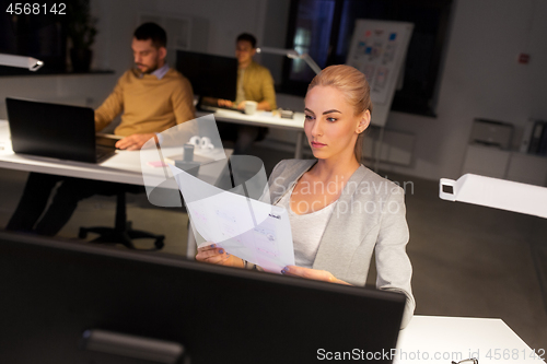 Image of designer working with papers at night office