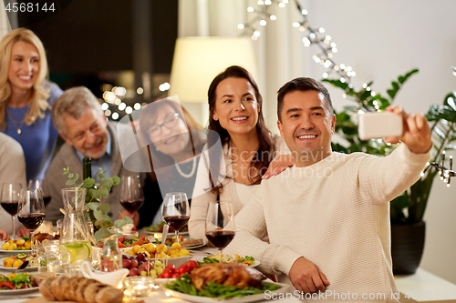 Image of family having dinner party and taking selfie