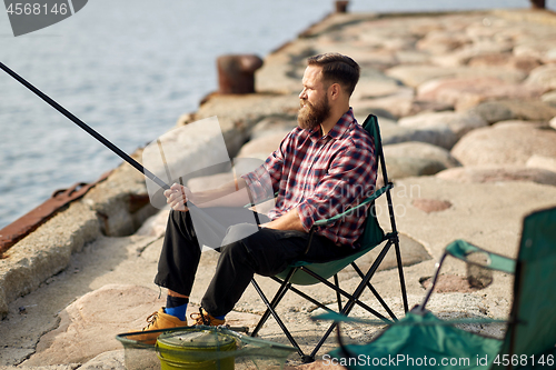 Image of happy friends with fishing rods on pier