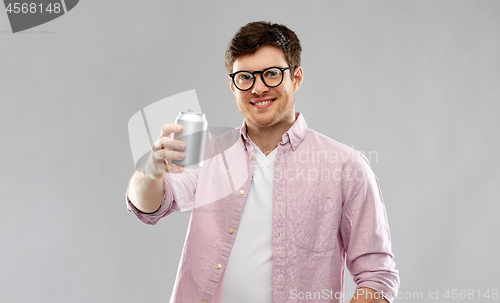 Image of happy young man drinking soda from tin can