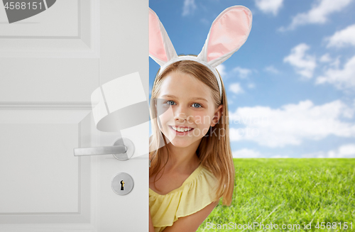 Image of happy girl with easter bunny ears peeking out door