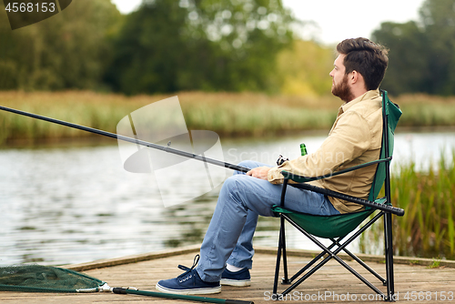 Image of bearded fisherman with fishing rod at lake