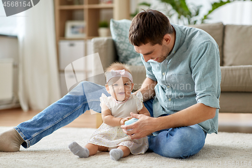 Image of father and little baby daughter with ball at home