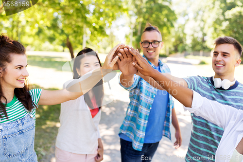 Image of happy friends making high five in park