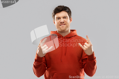 Image of young man in red hoodie showing rock sign