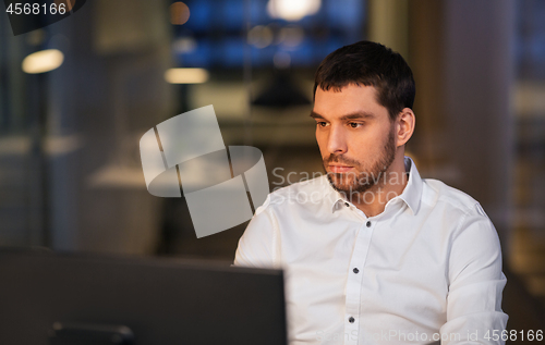 Image of businessman with computer working at night office