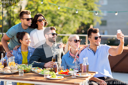 Image of happy friends taking selfie at rooftop party