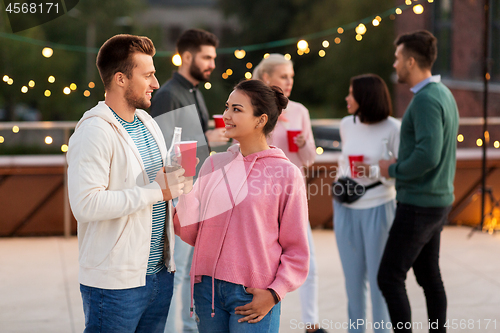 Image of friends with drinks in party cups at rooftop