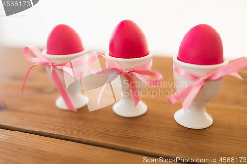 Image of three pink colored easter eggs in holders on table