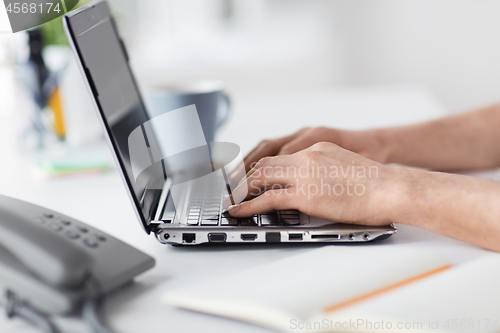 Image of hands typing on laptop computer at office