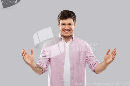 Image of smiling young man showing size of something