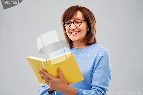 Image of portrait of senior woman in glasses reading book