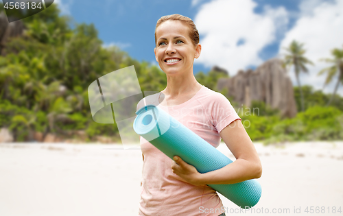 Image of happy smiling woman with exercise mat over beach