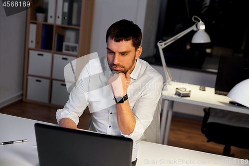 Image of businessman with laptop working at night office