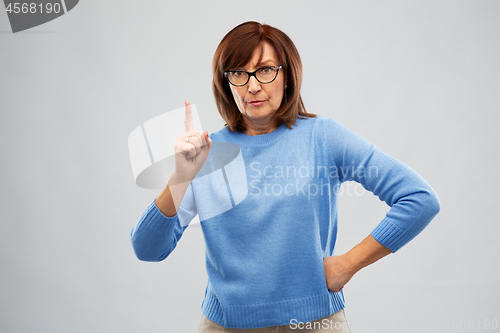 Image of displeased senior woman in glasses warning