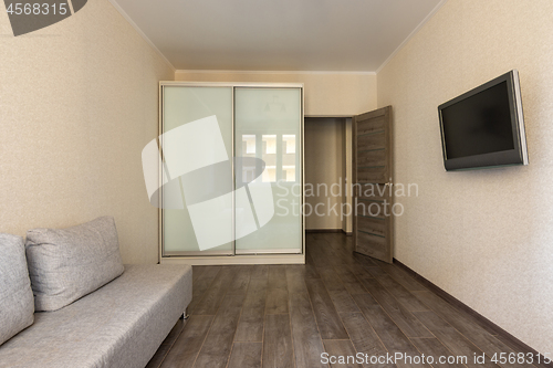 Image of Interior of a small modest room in a hotel, TV, wardrobe and sofa