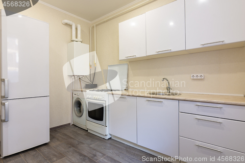 Image of Fragment of the interior of a small kitchen with a fridge and a kitchen set