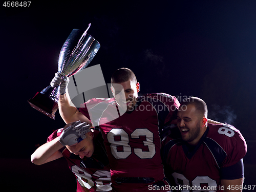 Image of american football team with trophy celebrating victory