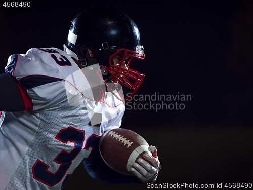 Image of American football player holding ball while running on field