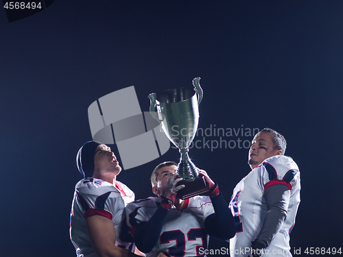 Image of american football team with trophy celebrating victory