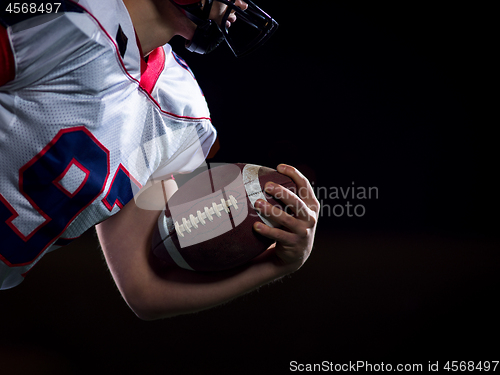 Image of American football player holding ball while running on field