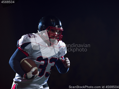 Image of American football player holding ball while running on field