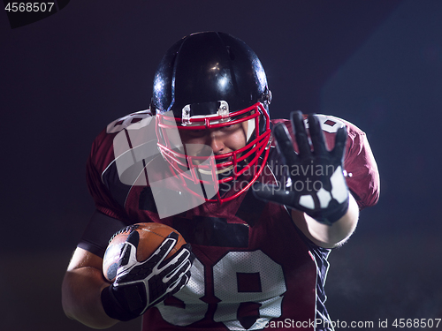 Image of American football player holding ball while running on field