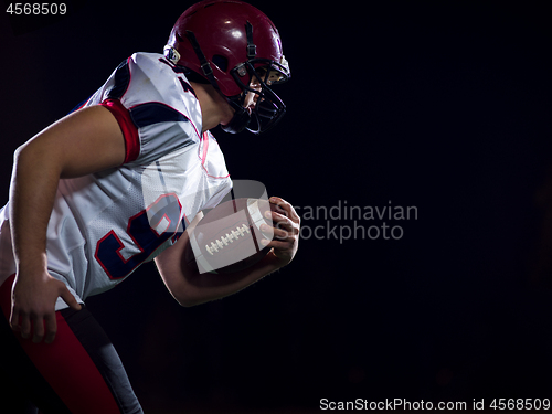 Image of American football player holding ball while running on field