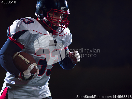 Image of American football player holding ball while running on field