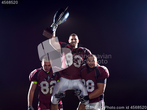 Image of american football team with trophy celebrating victory