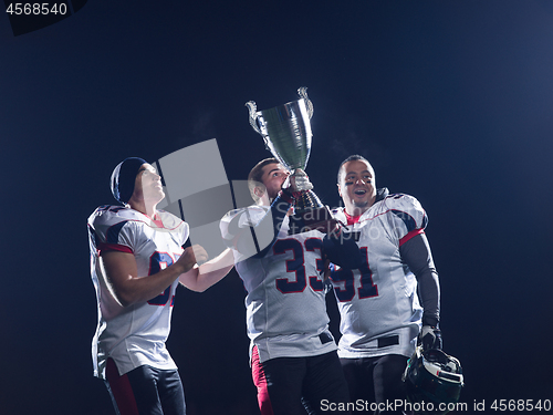 Image of american football team with trophy celebrating victory