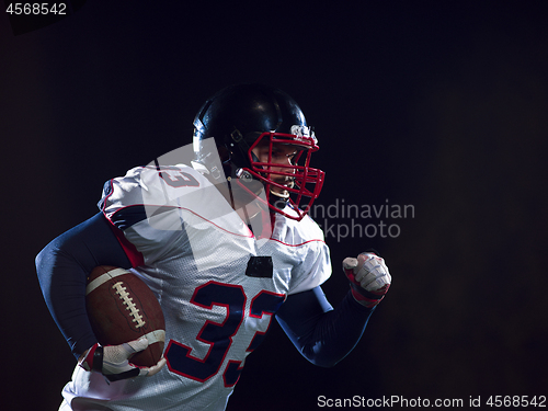 Image of American football player holding ball while running on field