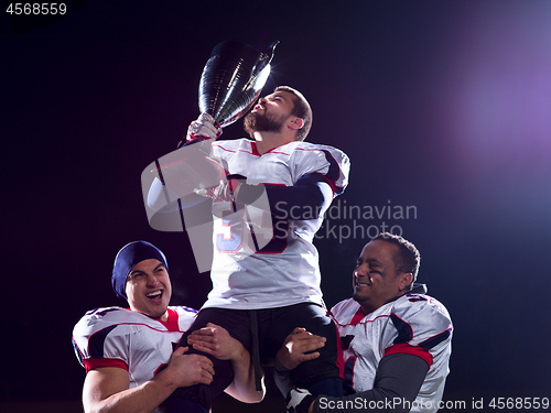 Image of american football team with trophy celebrating victory