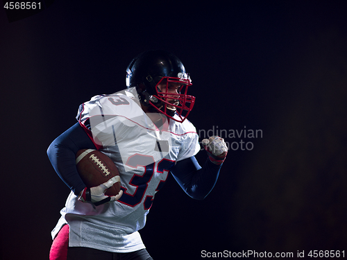 Image of American football player holding ball while running on field