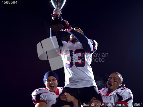 Image of american football team with trophy celebrating victory