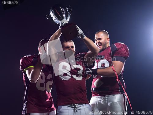 Image of american football team with trophy celebrating victory