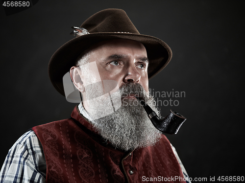 Image of dramatic portrait of senior smoking tobacco pipe