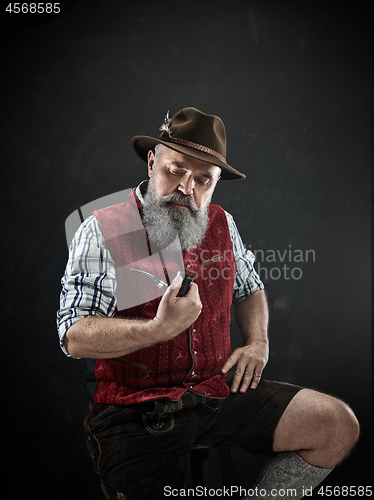 Image of dramatic portrait of senior smoking tobacco pipe