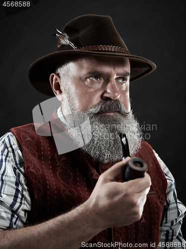 Image of dramatic portrait of senior smoking tobacco pipe