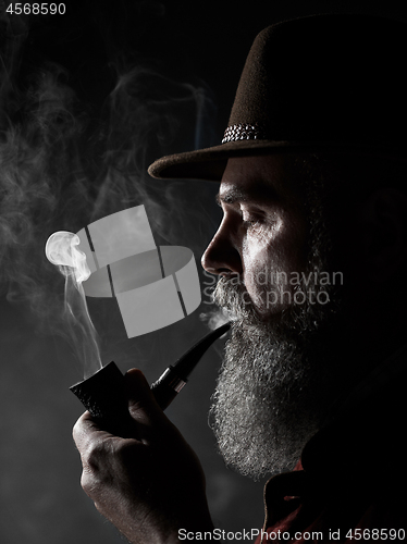 Image of dramatic portrait of senior smoking tobacco pipe